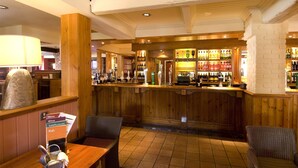 Eine Bar mit Holzwandverkleidung, einer Speisekarte auf Ständer und Sitzgelegenheiten.