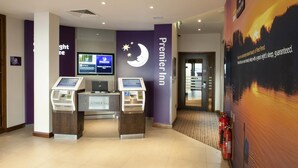 A hotel lobby with a check-in kiosk, a television screen, and a prominent Premier Inn sign. - Premier Inn Fleet (Fleet)