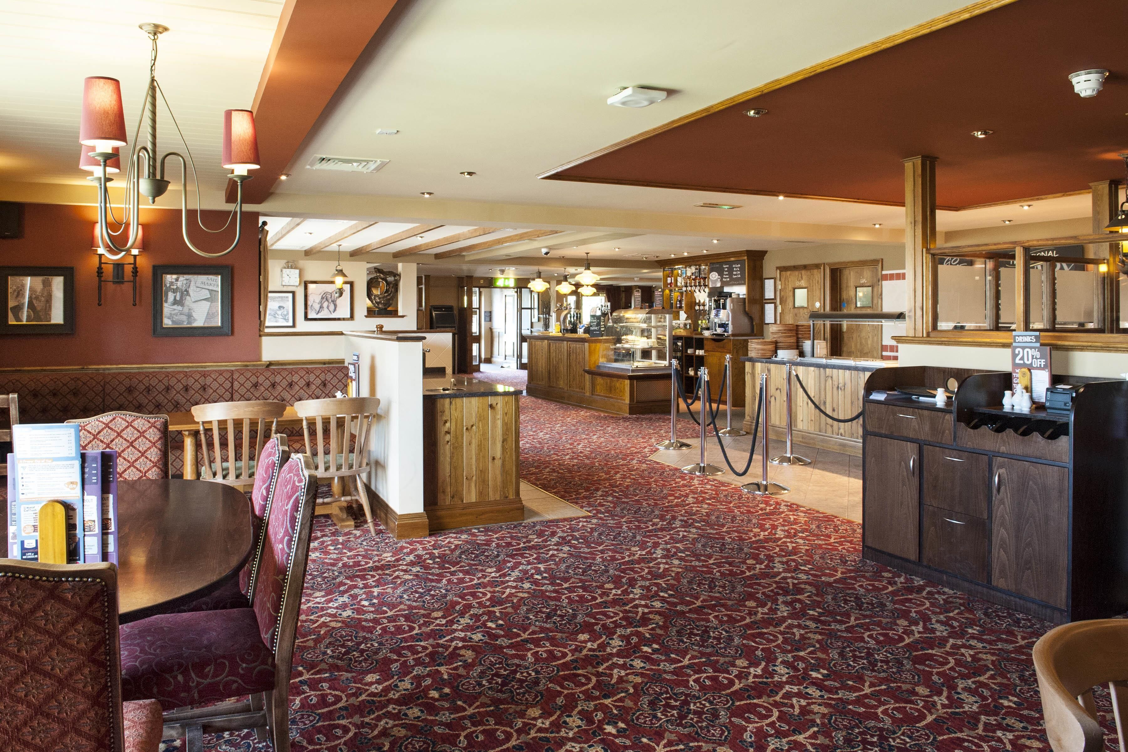 A restaurant with a bar area, wooden furniture, and a patterned carpet.