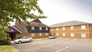 A hotel with a parking lot, a car in the lot, and a building with a dark facade and brick walls. - Premier Inn Ashford North (Ashford)
