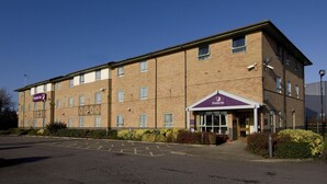 A two-story brick building with a flat roof, a visible entrance with a canopy, and a parking lot in front. - Premier Inn Ashford Central (Ashford)