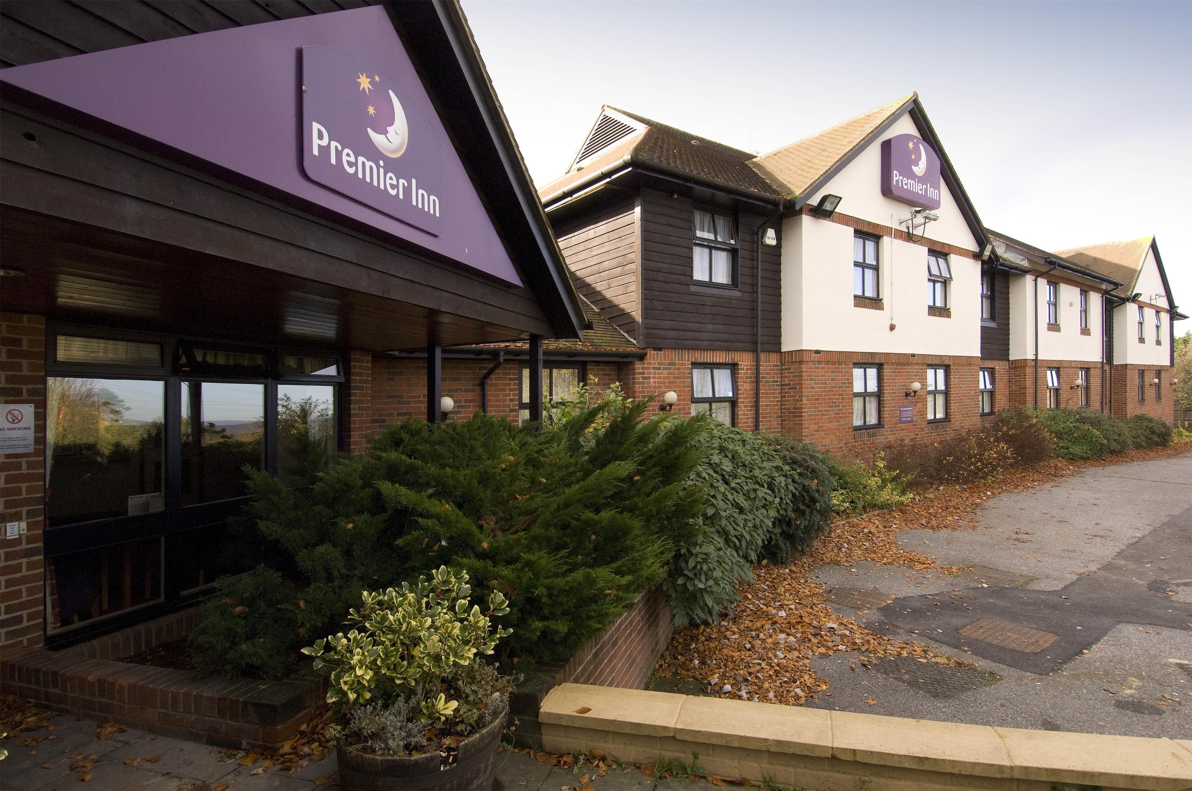 Um hotel Premier Inn com fachada de tijolos, grandes janelas e área de estacionamento.
