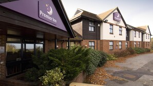 Un hôtel Premier Inn avec une façade en briques, de grandes fenêtres et un espace de stationnement.