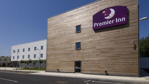 Un edificio moderno con un llamativo letrero de Premier Inn, fachada plana y una entrada pequeña.