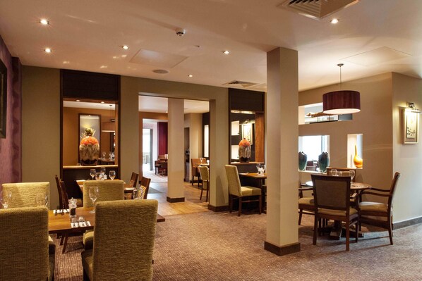 A hotel lobby with multiple dining areas, chairs, tables, and a large mirror. - Premier Inn Canterbury City Centre (Canterbury)