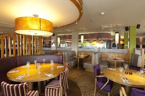 A restaurant with round tables, striped chairs, and a large hanging light fixture. - Premier Inn Swanley (Swanley)