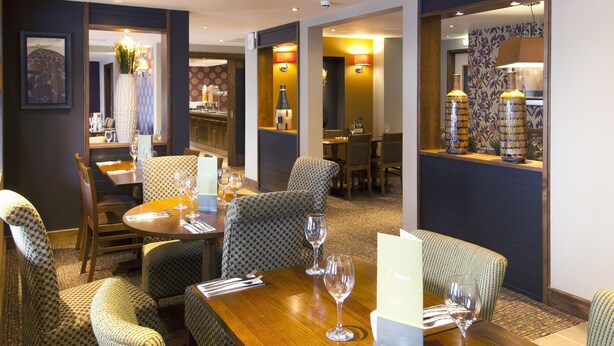 Un restaurant avec des chaises à motifs, une table en bois et des verres à vin.