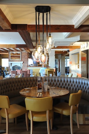A restaurant with a round table, leather booth seating, and hanging pendant lights.