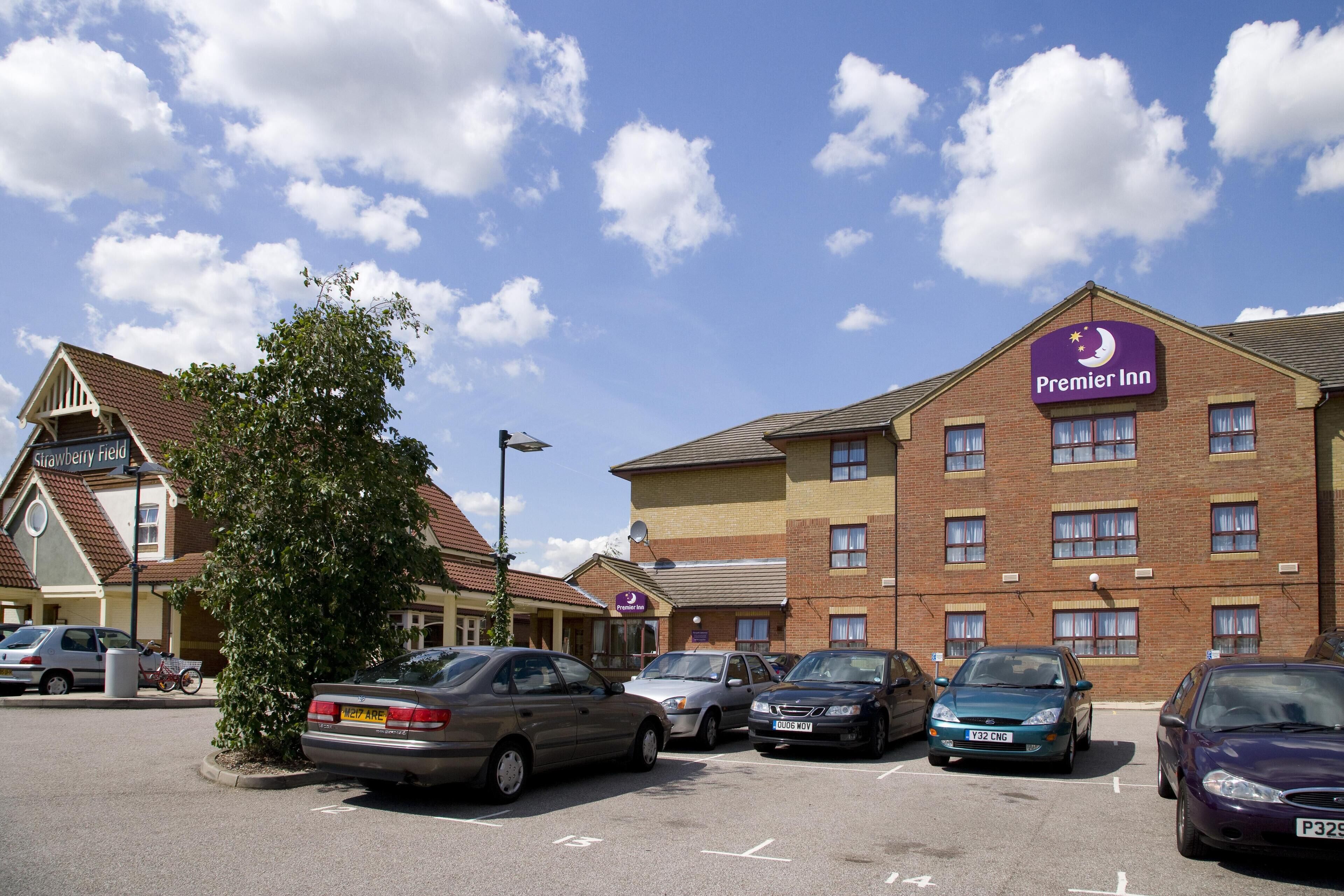 Un hotel Premier Inn con aparcamiento, edificios de ladrillo y cielo despejado.