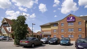 Un hotel Premier Inn con aparcamiento, edificios de ladrillo y cielo despejado.