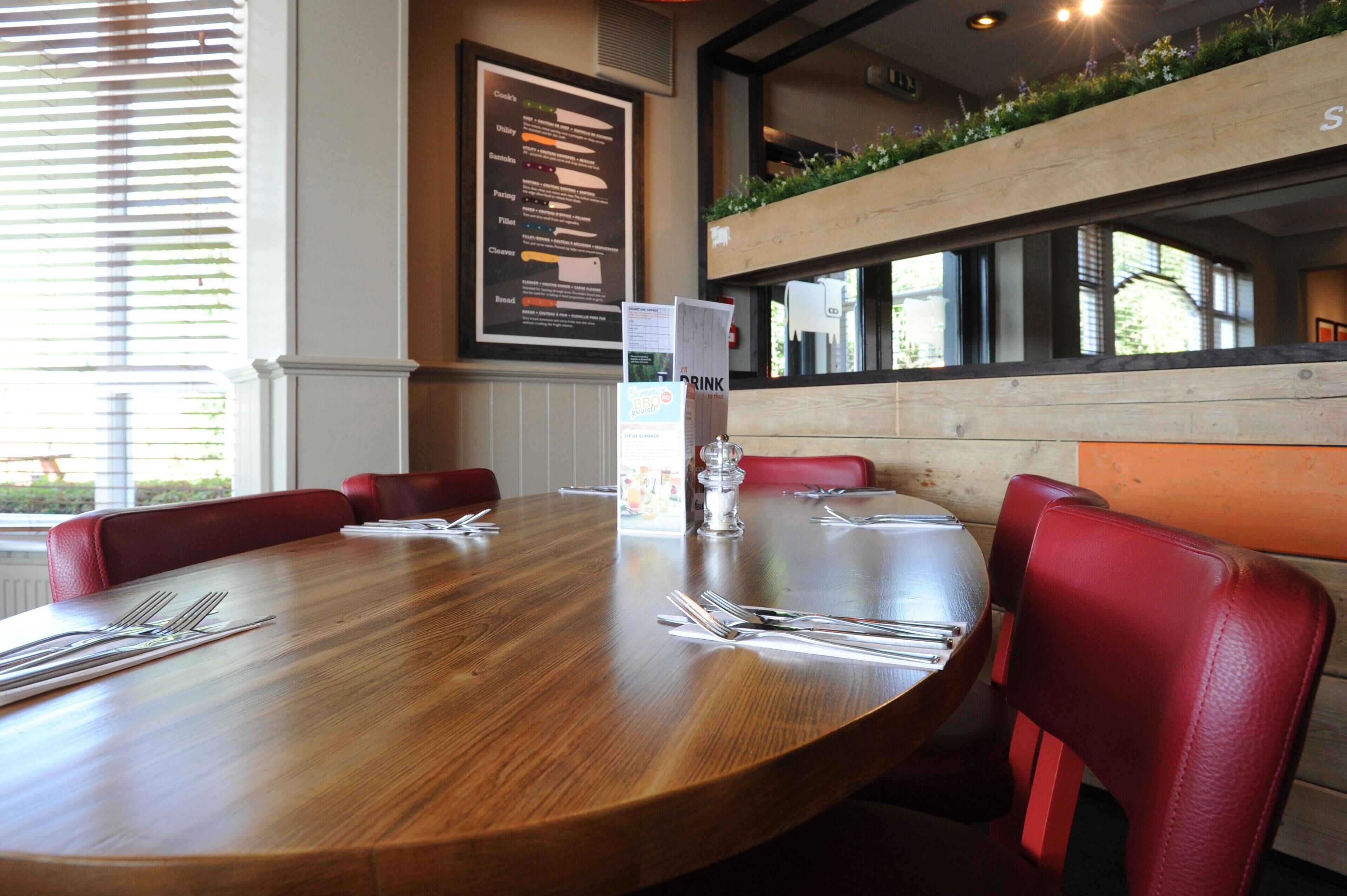 A conference table with chairs, a menu board, and a window with blinds.