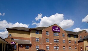 Un hotel de varios pisos con un llamativo letrero de Premier Inn, múltiples ventanas y fachada de ladrillo.