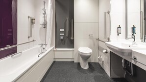 A modern bathroom with a bathtub, toilet, and shower.