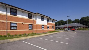 A multi-story building with a parking lot in front.