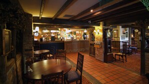 Un pub tradicional con una zona de bar, mesas y sillas de madera.