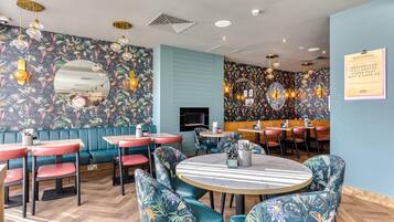 A restaurant with booths and tables, floral wall patterns, and a sign offering bottomless tea, coffee, and Wi-Fi.