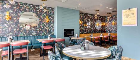 A restaurant with booths and tables, floral wall patterns, and a sign offering bottomless tea, coffee, and Wi-Fi.