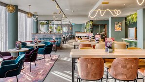 Ein modernes Restaurant mit runden Tischen, bunten Stühlen und Pendelleuchten.