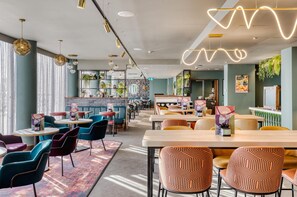 A modern restaurant with round tables, colorful chairs, and pendant lighting. - Premier Inn Southampton City Centre - West Quay (Southampton)