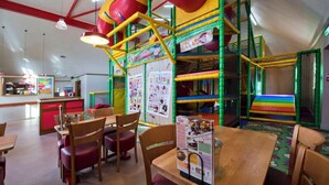 Zona de juegos infantiles con estructuras de escalada coloridas y un colchonete.