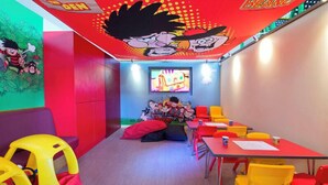 Un cuarto de juegos infantil con mobiliario colorido, un televisor y decoración con motivos de caricaturas.