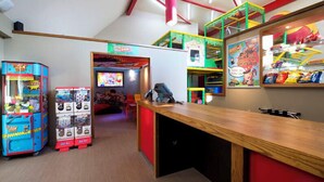 Un área de juegos infantiles con juegos de arcade, una estructura para jugar y un mostrador con aperitivos.