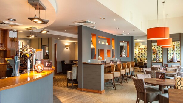 Un vestíbulo de hotel con mostrador de recepción, zona de estar y bar.
