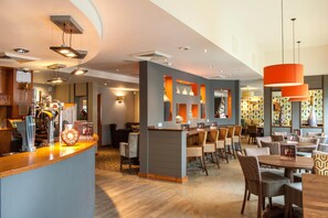 Um saguão de hotel com balcão de recepção, área de estar e bar.