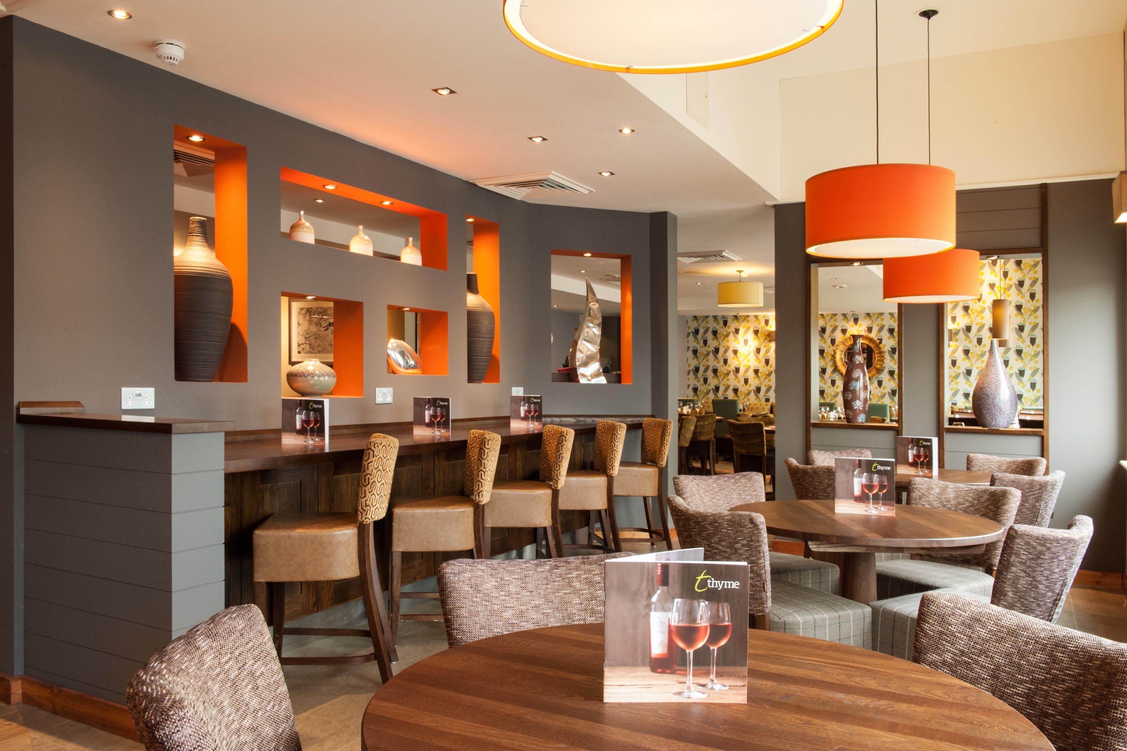 A restaurant with a bar area, multiple seating options, and a modern interior design.