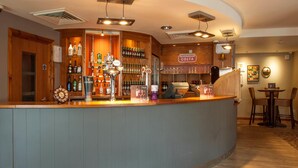 Zona de bar con una barra curva, estantes llenos de botellas de licor y un letrero que dice 'COSTA'.