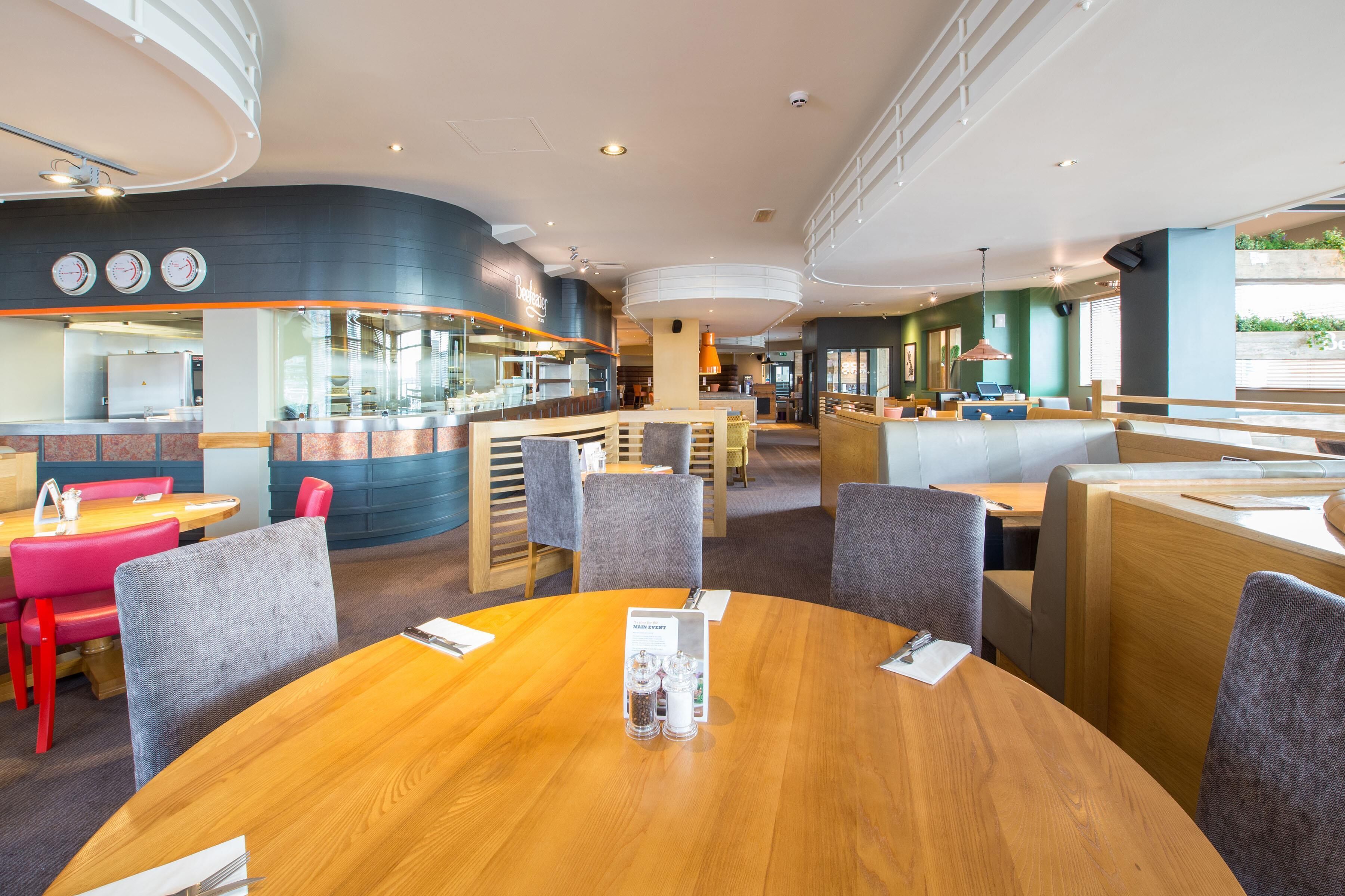 Un restaurant moderne avec des tables rondes, des chaises hautes et un coin bar.
