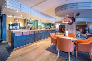 A modern bar area with a counter, seating, and a hanging pendant light. - Premier Inn Swansea Waterfront (Swansea)
