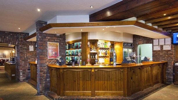 A bar area with wooden counter, stone walls, and various bottles. - Premier Inn Llanelli Central West (Llanelli)