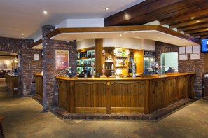 Un espace bar avec un comptoir en bois, des murs en pierre et diverses bouteilles.