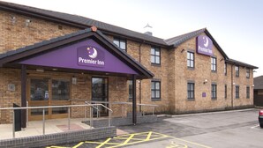 A Premier Inn hotel with a brick facade, large windows, and a purple awning. - Premier Inn Llanelli Central West (Llanelli)