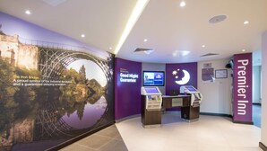 Vestíbulo de hotel con un gran mural del Puente de Hierro, un mostrador de recepción y un cartel que dice 'Good Night Guarantee'.