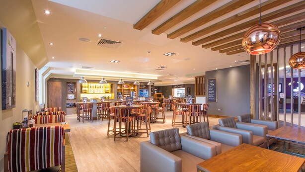Un amplio vestíbulo de hotel con varias zonas de estar, un bar y una recepción.