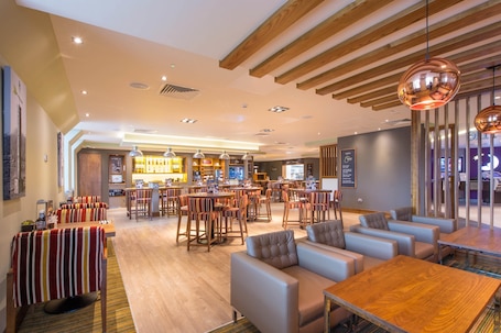A spacious hotel lobby with multiple seating areas, a bar, and a reception desk.