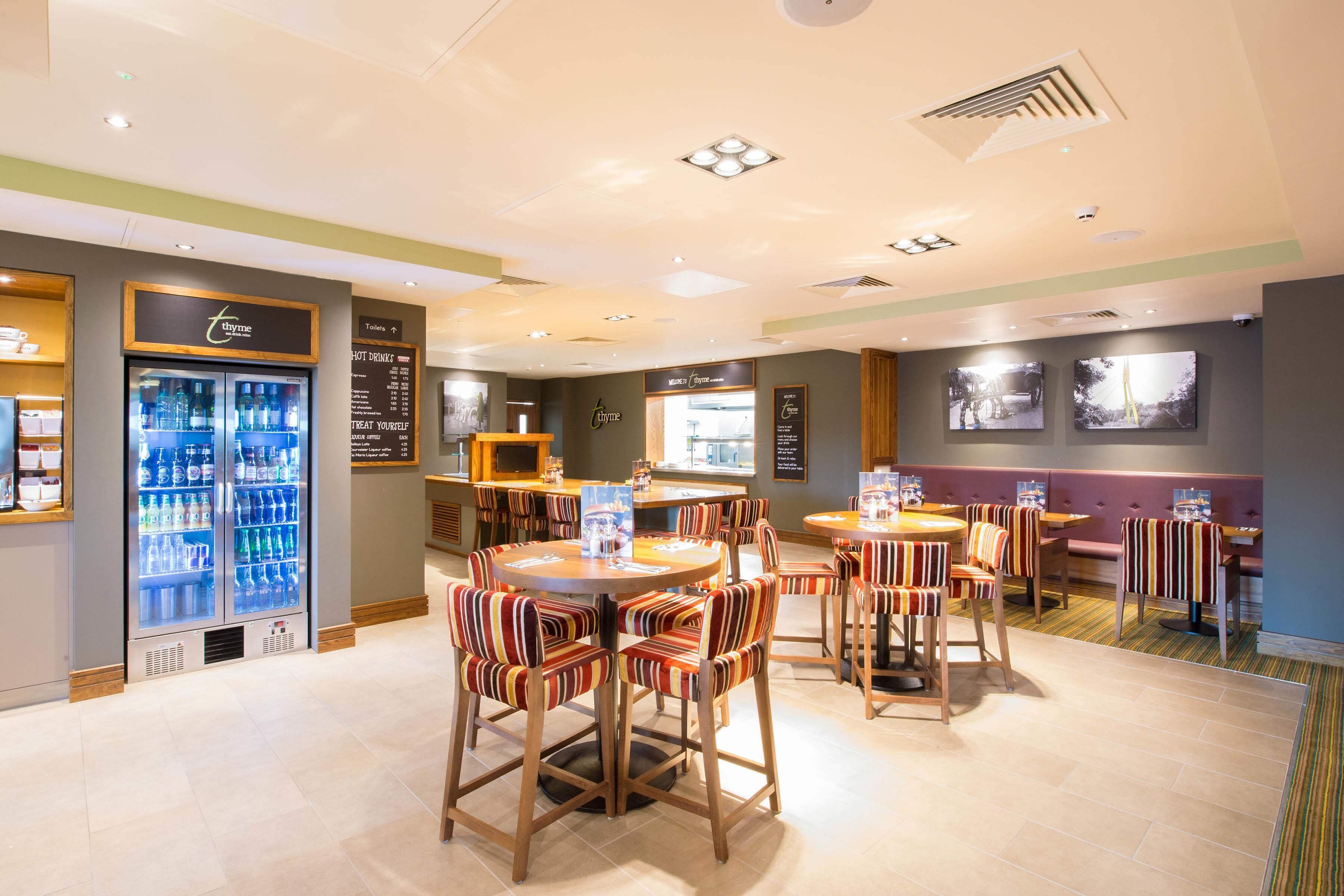 Un restaurante con mesas, sillas, un refrigerador para bebidas y una pizarra de menú.