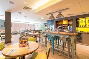 A restaurant with multiple dining tables, bar area, and a variety of seating options. - Premier Inn Tenby Town Centre (Tenby)