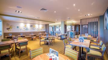 A restaurant with multiple seating areas, including booths and tables, with a variety of chairs and a patterned floor.