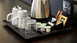A tray with a kettle, cups, glasses, and packaged snacks. - Premier Inn Newport Wales - M4 J24 (Newport)