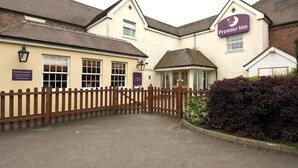 Ein Hotel namens 'Premier Inn' mit einem begrenzten Eingangsbereich, einer kleinen Veranda und einem Schild für Parkplatznutzer.