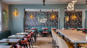 A restaurant interior with booths, high-top tables, and a herringbone wood floor. - Premier Inn Newport/Telford (Newport)