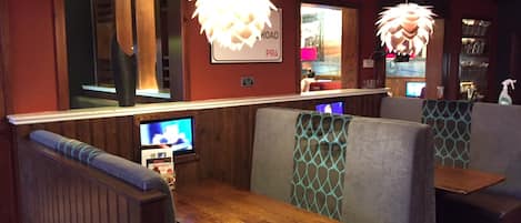 A restaurant interior with booths, wooden tables, and hanging pendant lights.