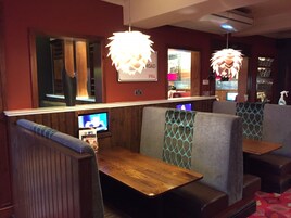 Interior de un restaurante con cabinas, mesas de madera y lámparas colgantes.
