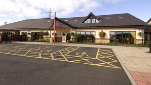 A building with a parking lot marked with disabled parking signs and a wheelchair symbol. - Premier Inn Blackburn South - M65 J4 (Darwen)