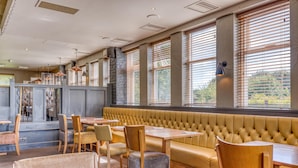 A restaurant with a long bench seating area, wooden tables, and chairs. - Premier Inn Basingstoke West (Basingstoke)