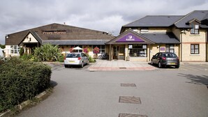 Ein Hotel mit einem Schild 'Priory Marina', einem Schild 'Premier Inn' und zwei geparkten Autos davor.
