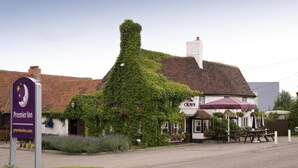 En byggnad med murgrönebeklädda väggar, en skylt med texten ”Premier Inn” och utomhusplatser.